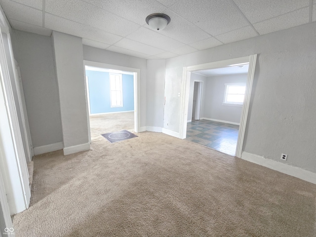 unfurnished room with carpet floors and a drop ceiling