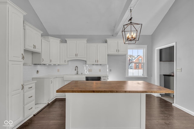 kitchen with wooden counters, sink, hanging light fixtures, white cabinets, and lofted ceiling with beams