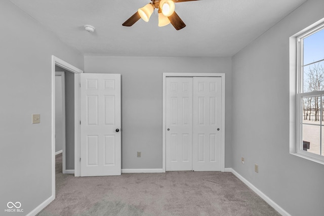 unfurnished bedroom featuring ceiling fan, light colored carpet, and a closet