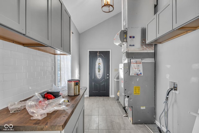 kitchen with vaulted ceiling, heating unit, wooden counters, and gray cabinets