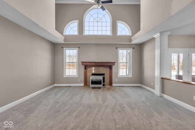 unfurnished living room with ceiling fan, light colored carpet, a towering ceiling, and a premium fireplace