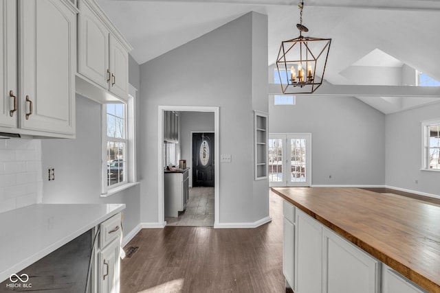 kitchen featuring a healthy amount of sunlight, white cabinets, wooden counters, and decorative light fixtures