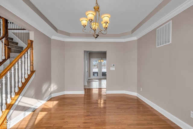 unfurnished dining area featuring a chandelier, crown molding, and a raised ceiling