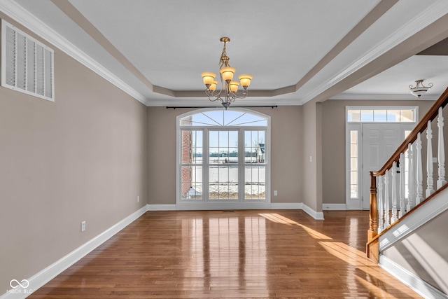 unfurnished dining area featuring a raised ceiling, a wealth of natural light, and a chandelier