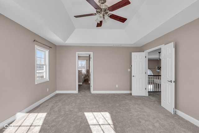 unfurnished bedroom with ceiling fan, light colored carpet, and a tray ceiling