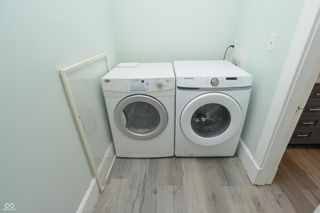 laundry room with light wood-type flooring and washing machine and clothes dryer