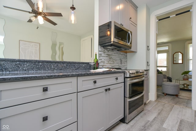 kitchen with tasteful backsplash, ceiling fan, pendant lighting, light wood-type flooring, and appliances with stainless steel finishes