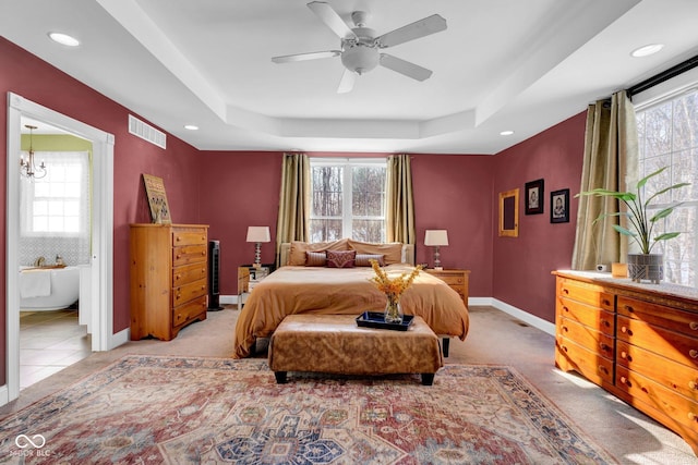 bedroom with light colored carpet, ceiling fan with notable chandelier, and a raised ceiling