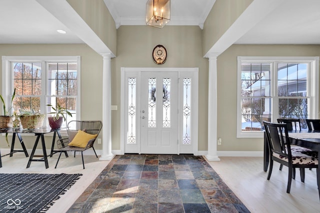 foyer with an inviting chandelier, crown molding, and ornate columns