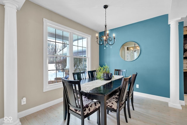 dining area with light wood-type flooring, a chandelier, and ornate columns