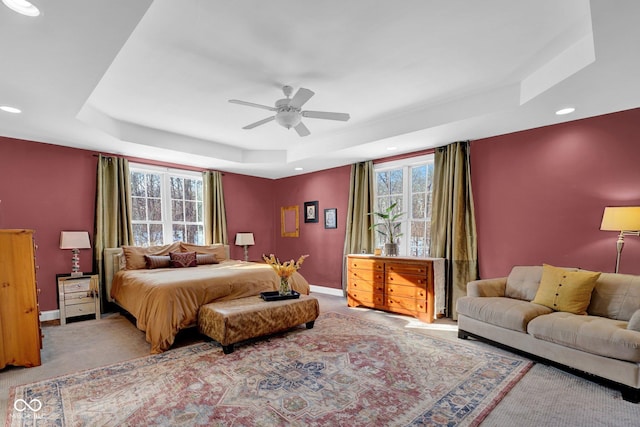 carpeted bedroom with ceiling fan and a tray ceiling