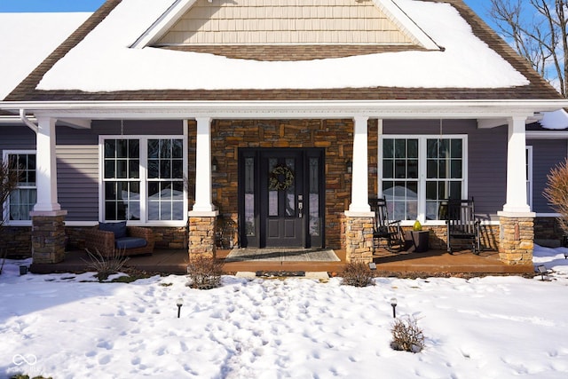 snow covered property entrance with covered porch