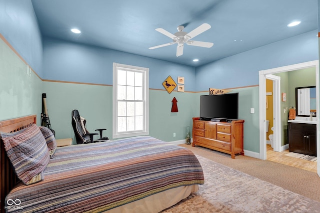 bedroom featuring ceiling fan, connected bathroom, and light colored carpet