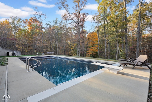 view of swimming pool with a diving board and a patio