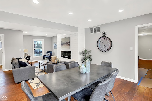 dining room featuring a large fireplace and dark hardwood / wood-style flooring