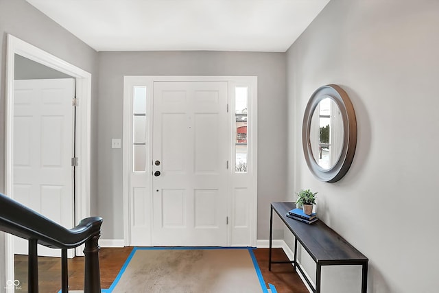 foyer entrance with dark wood-style floors and baseboards