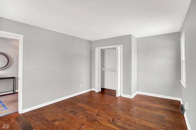 unfurnished bedroom with a closet and dark hardwood / wood-style flooring