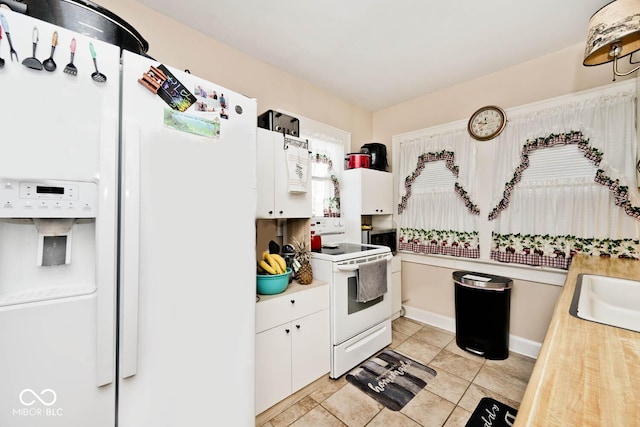 kitchen with white cabinets, sink, light tile patterned floors, and white appliances