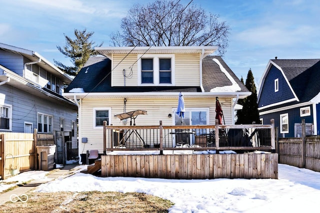 snow covered back of property with a deck