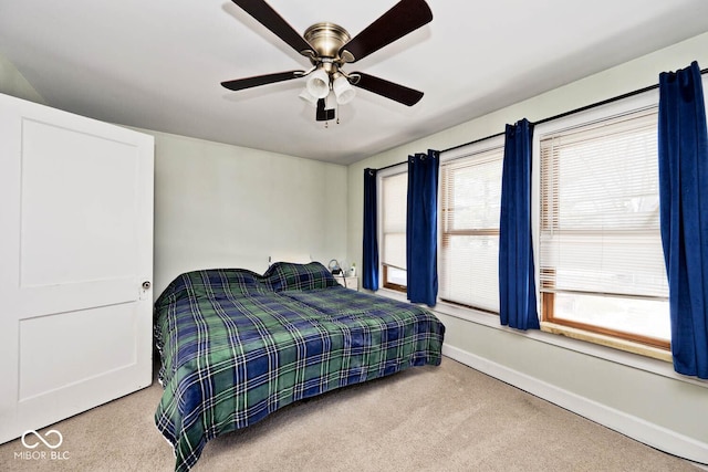 bedroom featuring ceiling fan, light carpet, and multiple windows