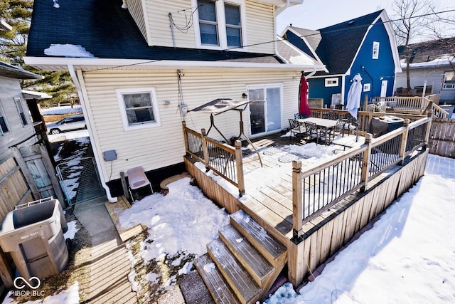 snow covered house with a wooden deck