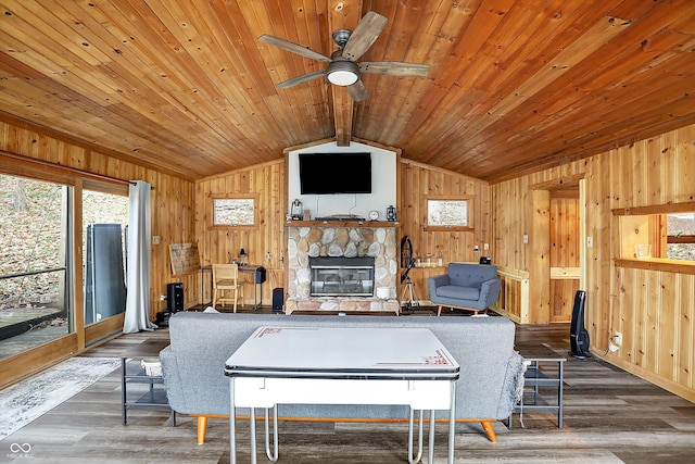 recreation room featuring lofted ceiling with beams, wooden walls, dark hardwood / wood-style floors, ceiling fan, and a fireplace