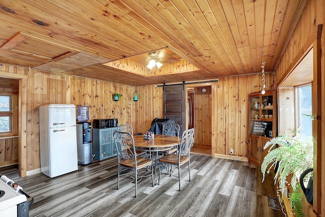 dining room featuring wood ceiling, wood-type flooring, a barn door, and wood walls