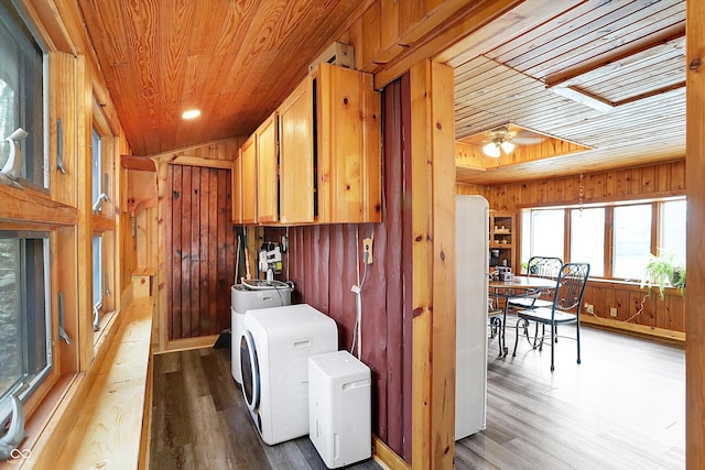 laundry area with separate washer and dryer, light wood-type flooring, wood ceiling, and wood walls