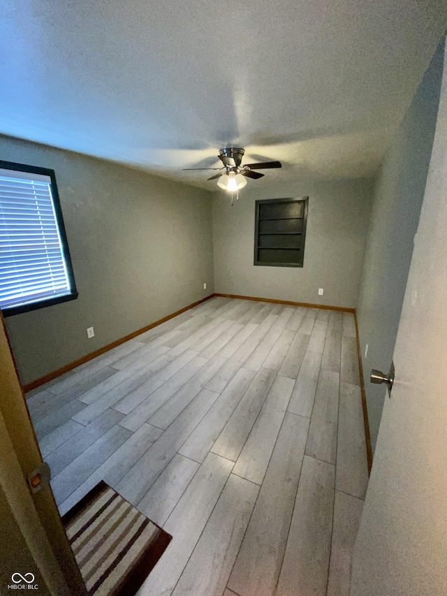 unfurnished room featuring ceiling fan, light wood-type flooring, and a textured ceiling