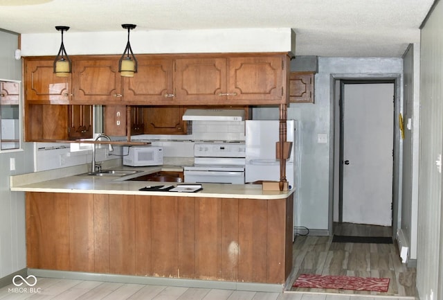 kitchen featuring exhaust hood, kitchen peninsula, white appliances, hanging light fixtures, and sink