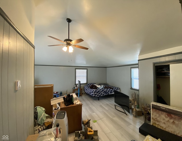 bedroom featuring ceiling fan, light hardwood / wood-style floors, multiple windows, and a closet