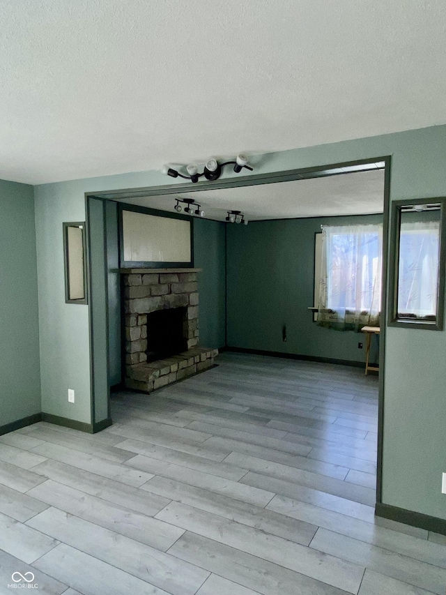 unfurnished living room with light wood-type flooring and a stone fireplace