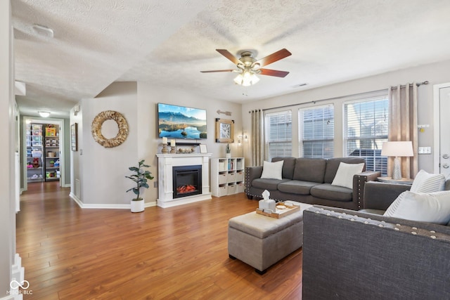 living room with hardwood / wood-style flooring, ceiling fan, and a textured ceiling