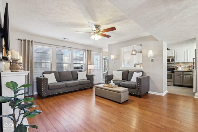 living room featuring hardwood / wood-style flooring, a textured ceiling, and ceiling fan