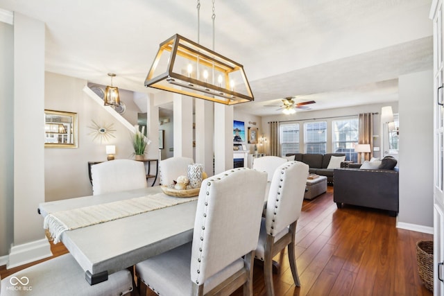 dining area with dark wood-type flooring and ceiling fan with notable chandelier