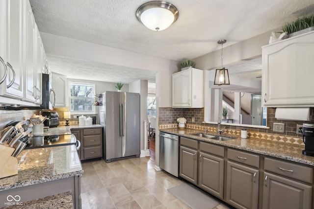 kitchen featuring sink, gray cabinets, white cabinetry, stainless steel appliances, and dark stone counters