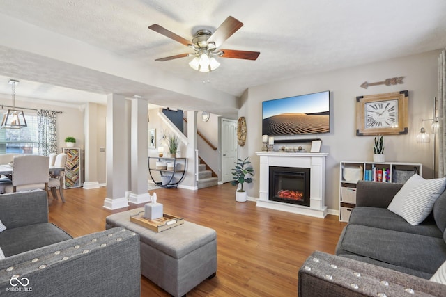 living room with hardwood / wood-style flooring, ceiling fan, and a textured ceiling