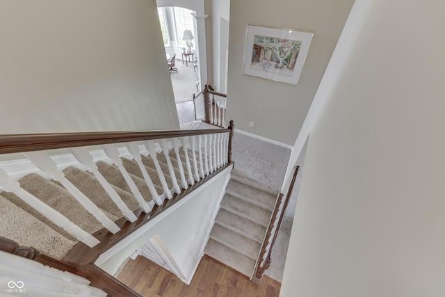 staircase with ornate columns and hardwood / wood-style floors