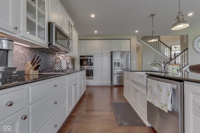 kitchen with stainless steel appliances, decorative backsplash, white cabinetry, and decorative light fixtures