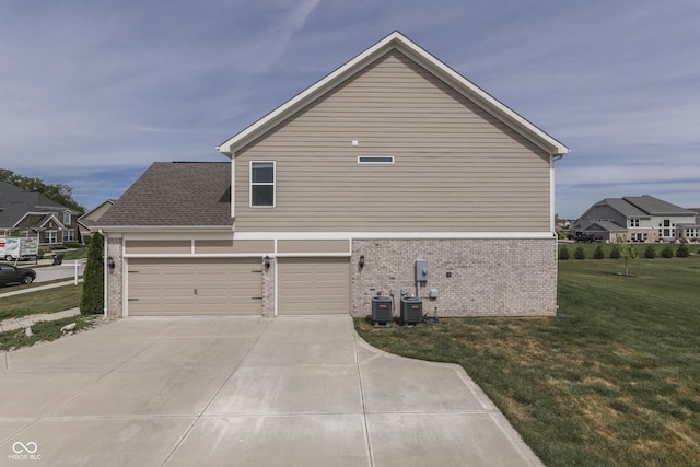 view of side of home with central AC unit, a yard, and a garage