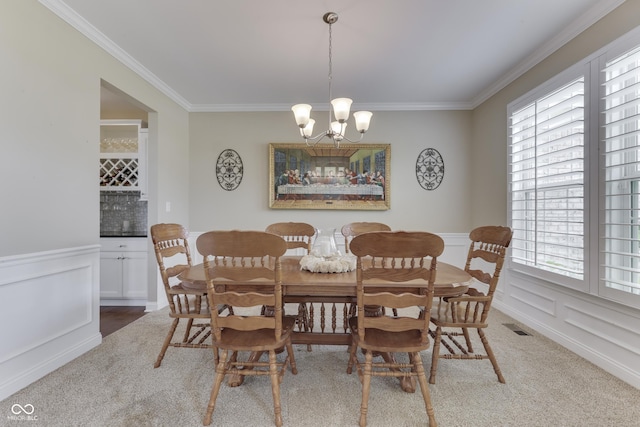 dining area featuring crown molding, carpet, and an inviting chandelier