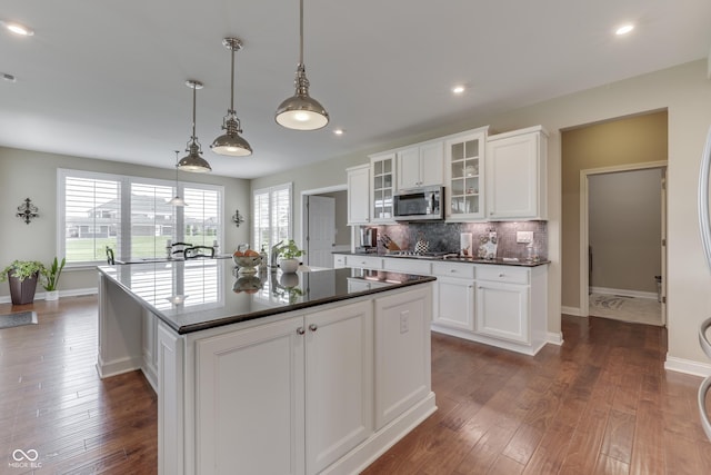 kitchen with decorative light fixtures, white cabinetry, appliances with stainless steel finishes, and a kitchen island