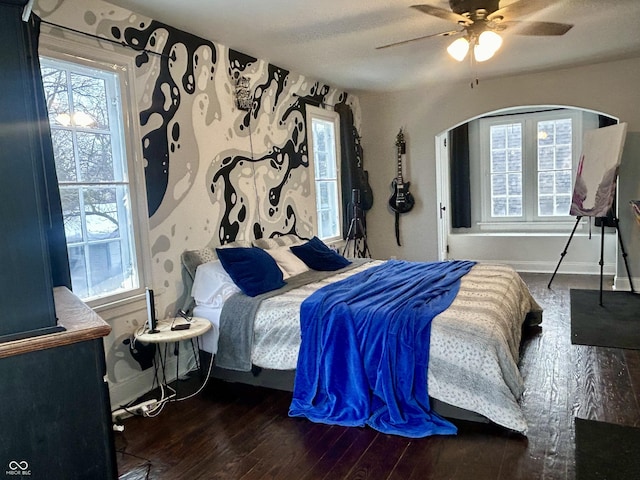 bedroom with ceiling fan, dark wood-type flooring, and multiple windows