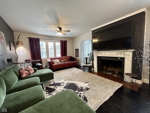 living room featuring ceiling fan, dark hardwood / wood-style floors, and a fireplace