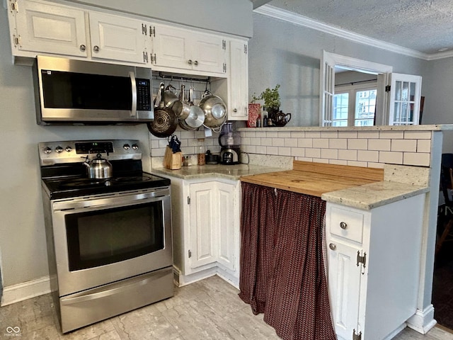 kitchen with backsplash, white cabinetry, appliances with stainless steel finishes, and ornamental molding