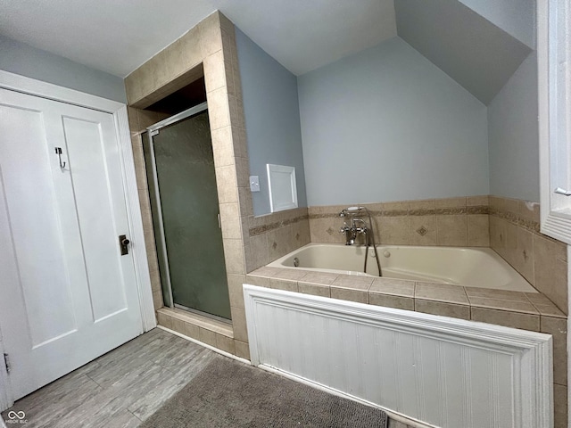 bathroom with hardwood / wood-style flooring, vaulted ceiling, and shower with separate bathtub