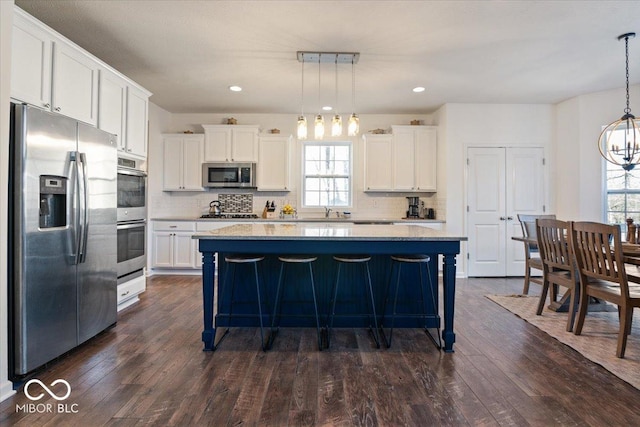 kitchen featuring stainless steel appliances, a kitchen island, hanging light fixtures, and white cabinets