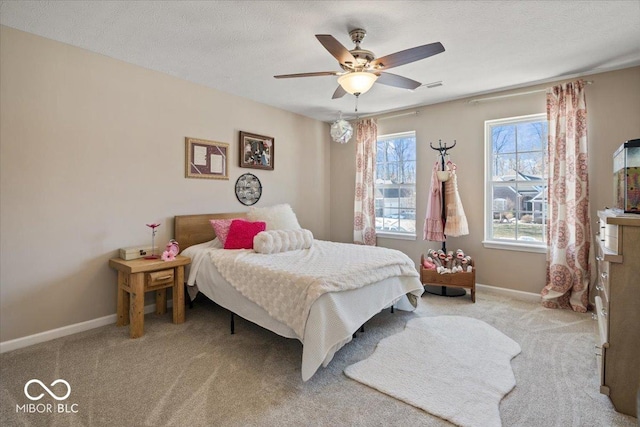 bedroom featuring a textured ceiling, light colored carpet, and ceiling fan