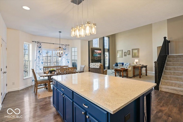 kitchen with blue cabinetry, a center island, a notable chandelier, dark hardwood / wood-style flooring, and decorative light fixtures