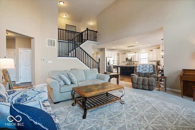 carpeted living room featuring a towering ceiling and a notable chandelier